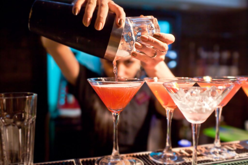 female bartender pouring pink martini drinks